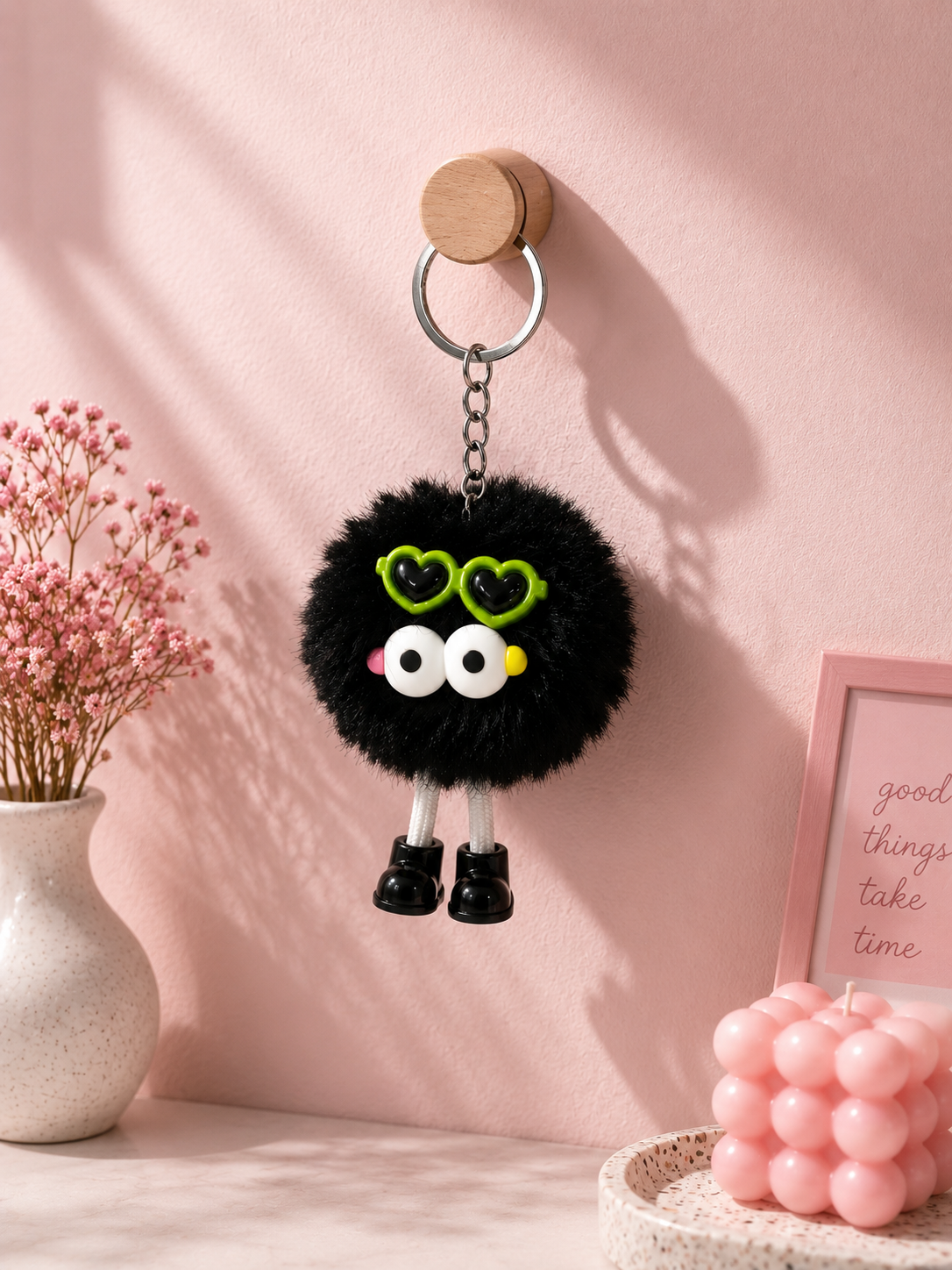 Black plush bear keychain with green heart-shaped eyes, white muzzle, yellow nose, metal key ring.