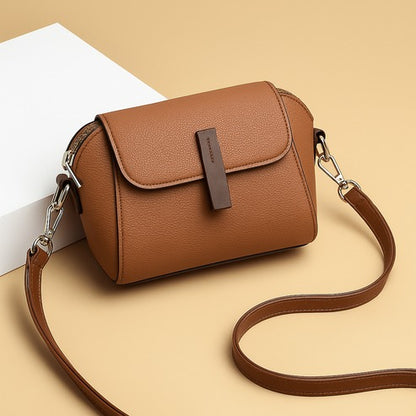 Brown textured leather flap crossbody bag with front tab and chain strap