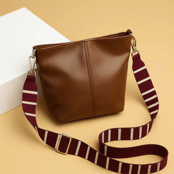 Brown leather-look tote bag with top zipper and striped shoulder strap with gold hardware