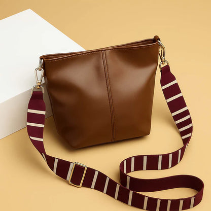 Brown leather-look tote bag with top zipper and striped shoulder strap with gold hardware