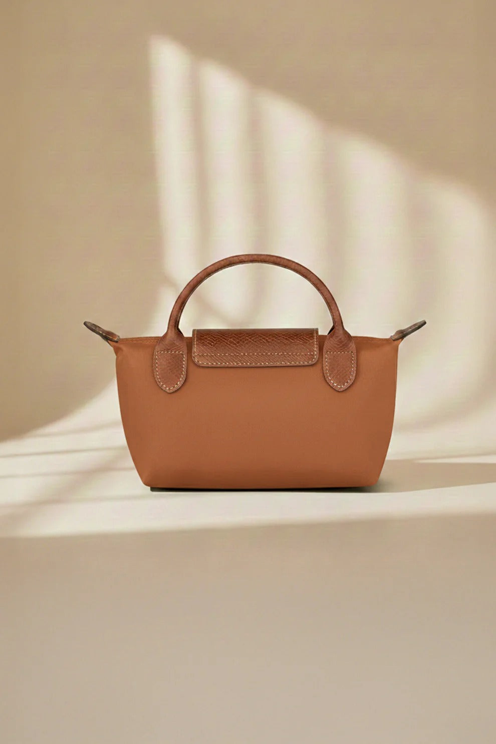 Brown crossbody bag with structured shape, short handles, and front snap pocket