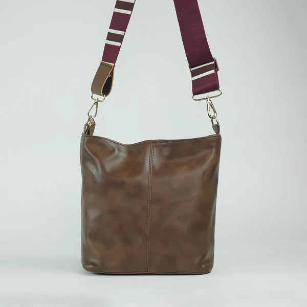 Brown leather tote bag with striped adjustable crossbody strap and metal clips