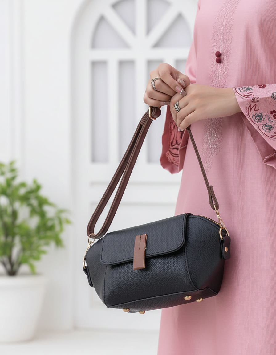 Dark small crossbody handbag with flap front and long brown shoulder strap