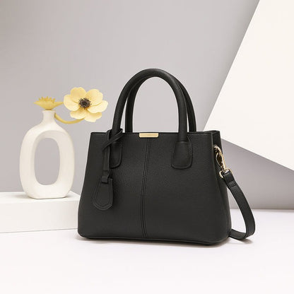Black leather handbag with gold clasp, double top handles, and detachable crossbody strap